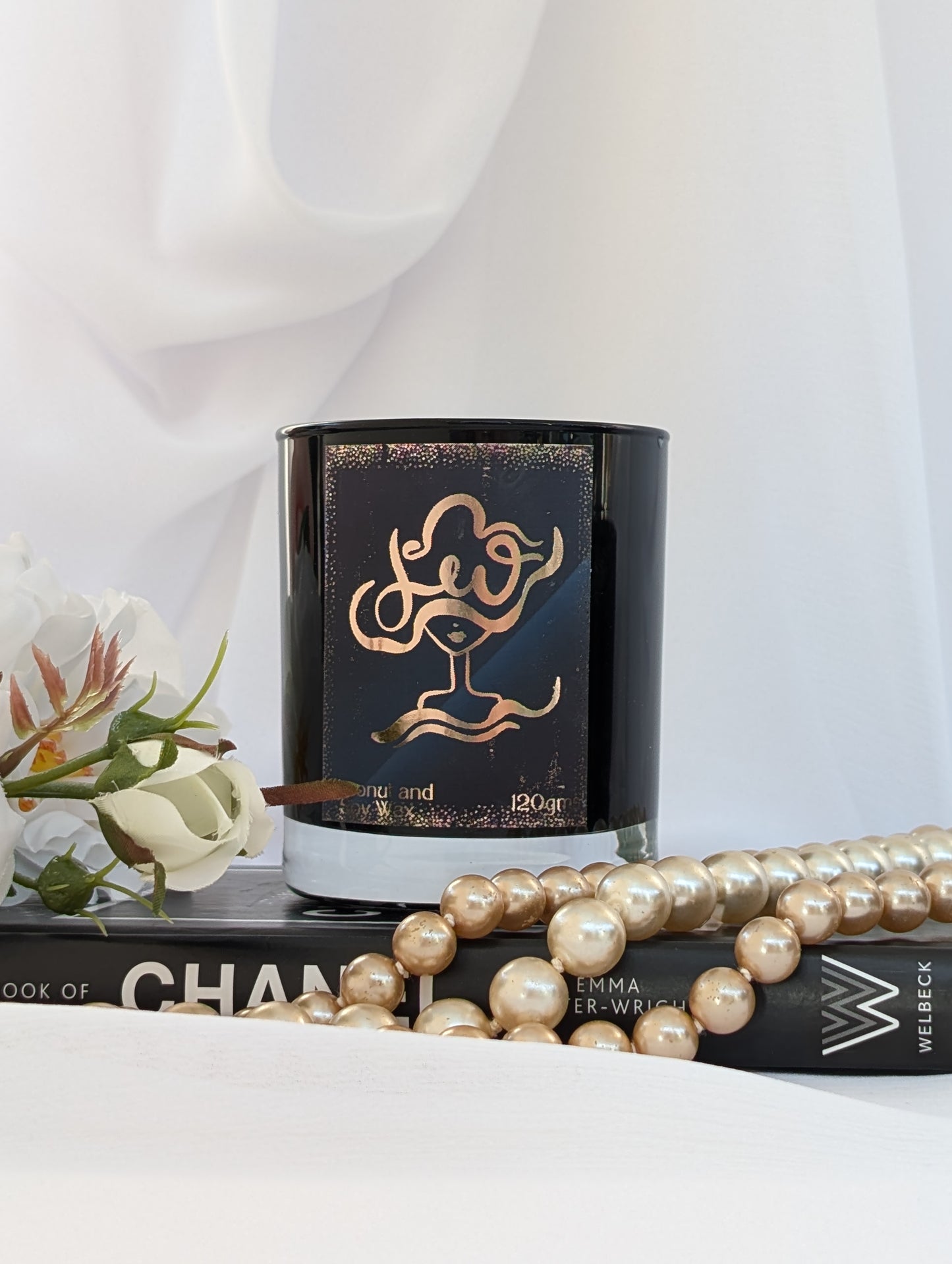 Black and Gold Leo Zodiac Candle on black book with pearls and flowers