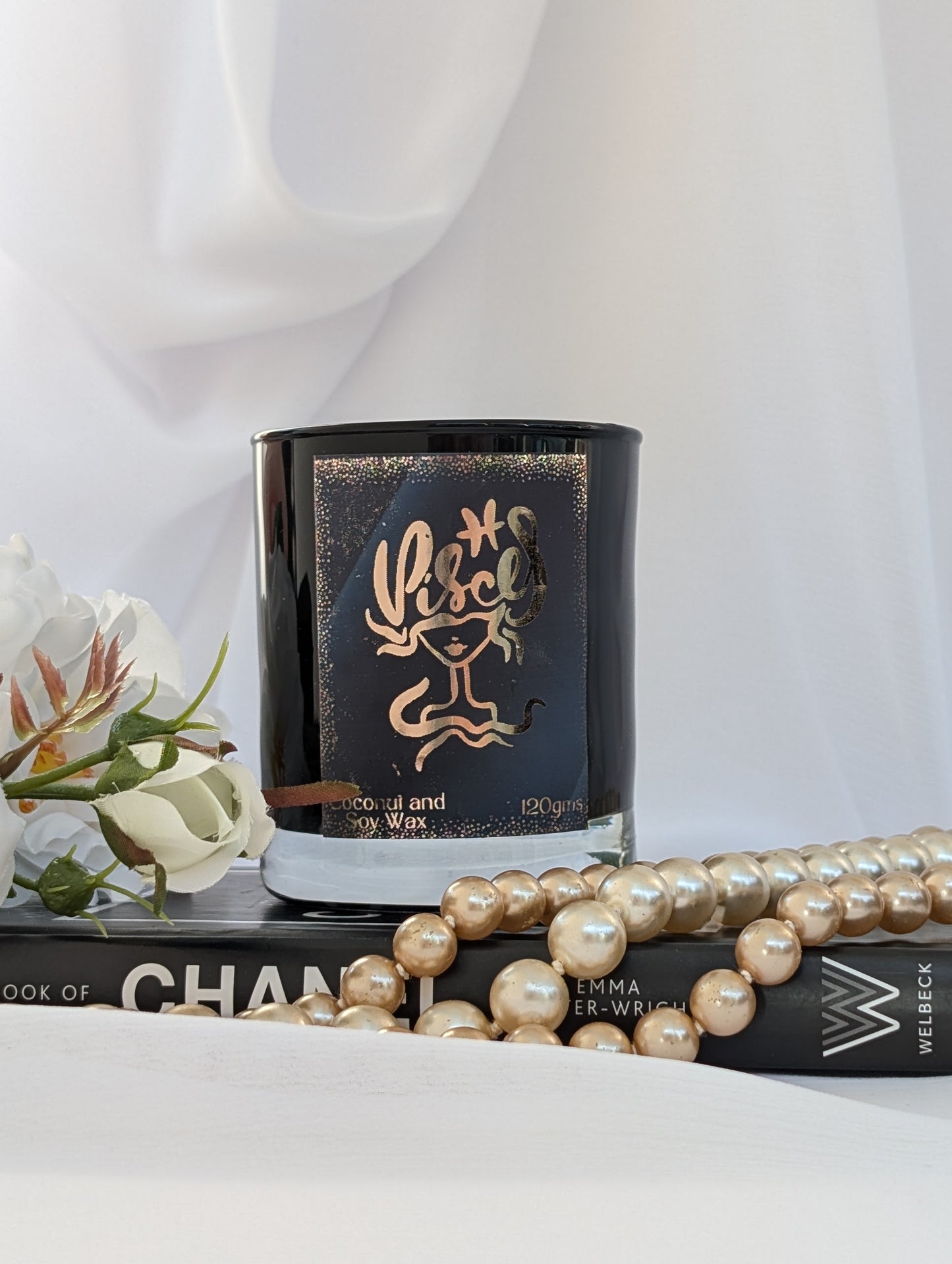Black and Gold Pisces Candle on black book with pearls and flowers