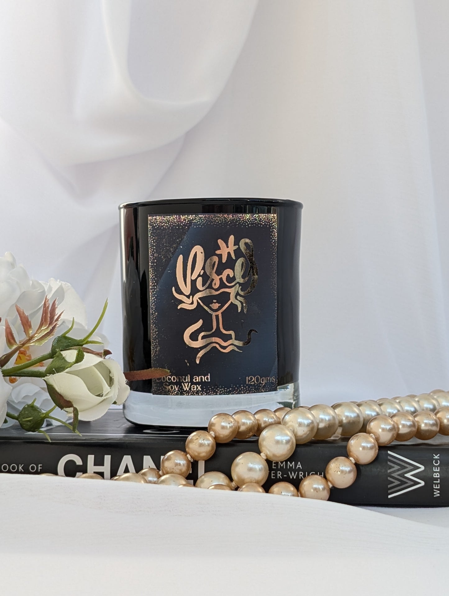 Black and Gold Pisces Zodiac Candle on black book with pearls