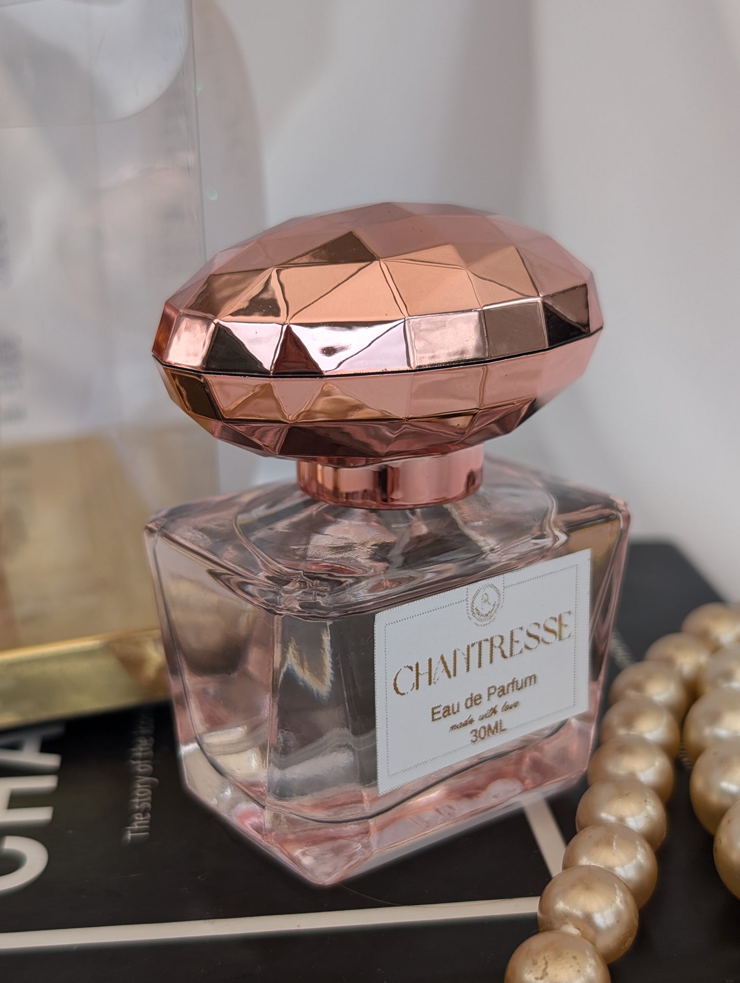 Perfume bottle with rose gold cap on a surface with a blurred background
