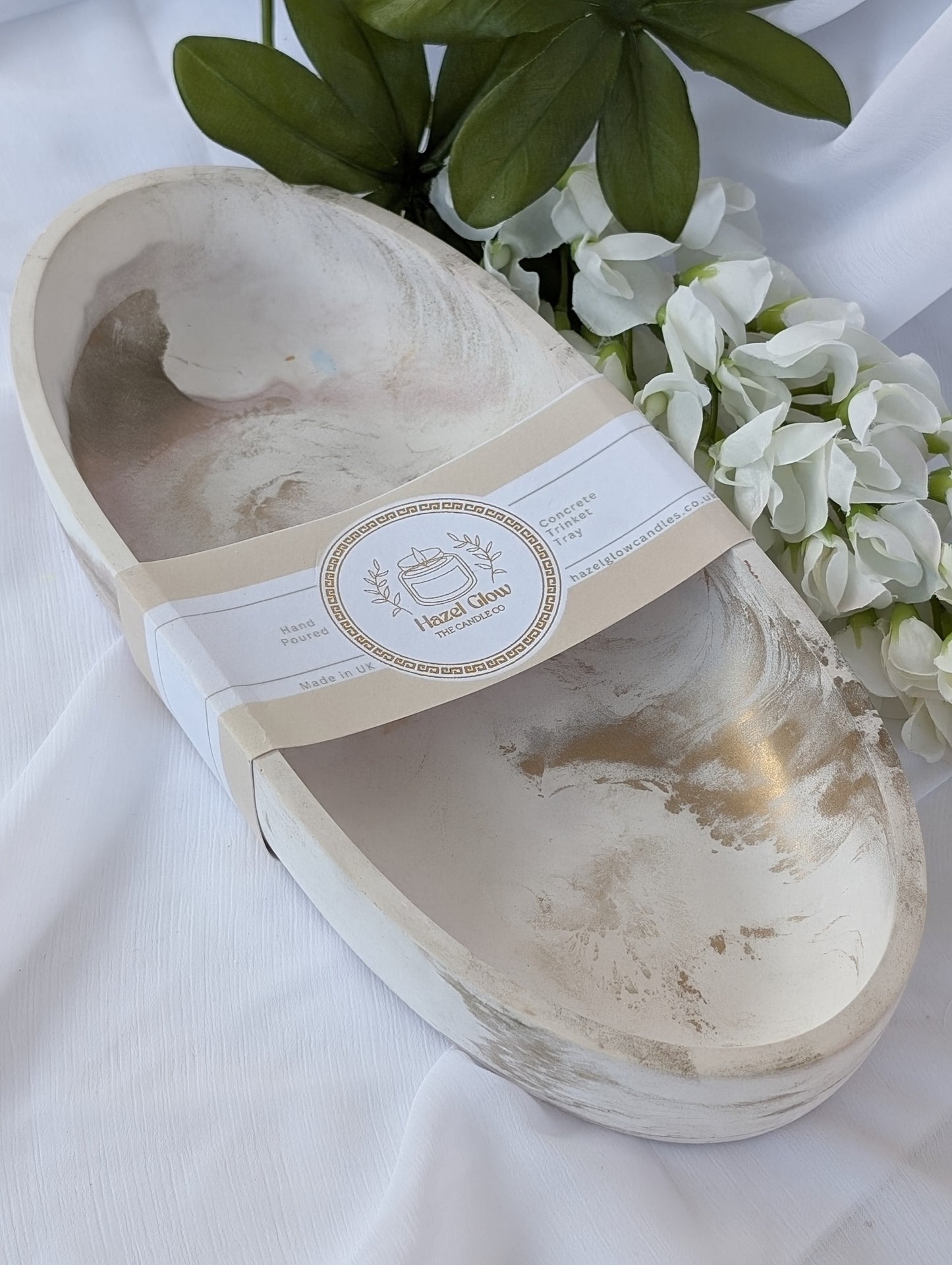 Marble effect oval stoneware dish with a label on a white fabric background with flowers