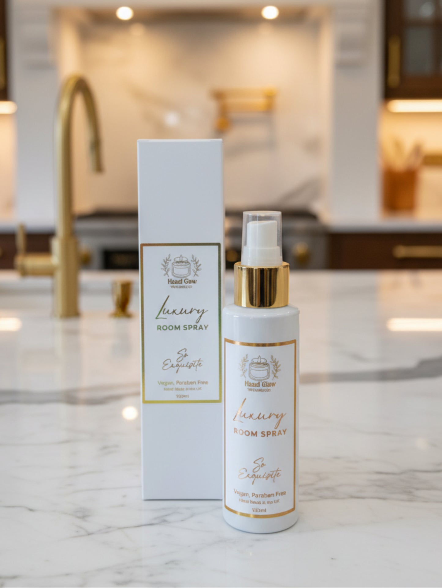 Home fragrance luxury room spray by Hazel Glow. So Exquisite fragrance - vegan, cruelty free, paraben free. White bottle with gold cap and white and gold label with white box packaging on a marble counter in a luxury kitchen