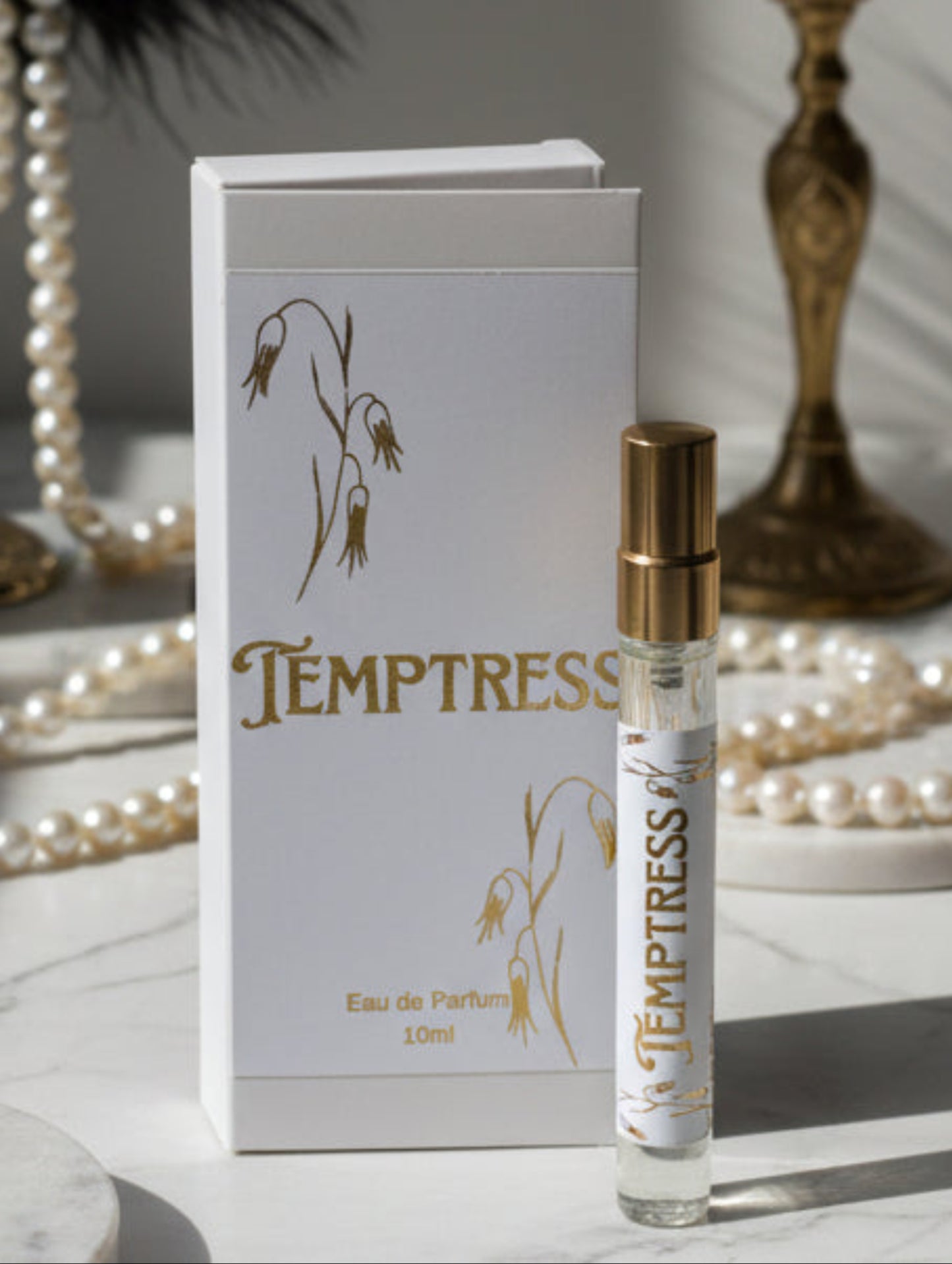 Temptress eau de parfum bottle and packaging on a marble surface