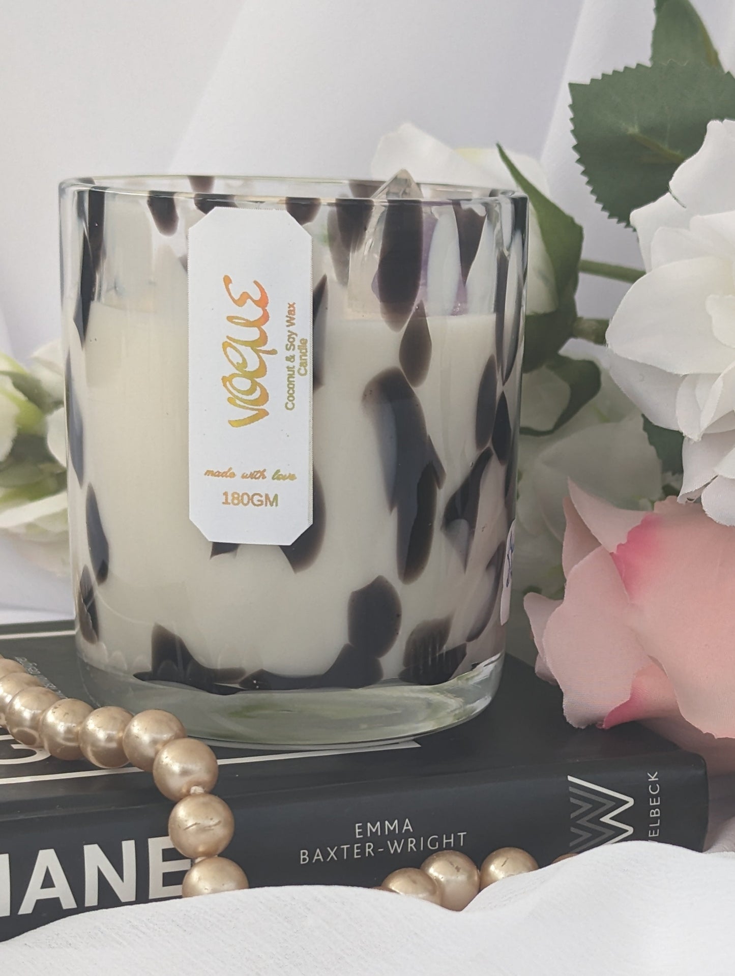 Vogue Luxury Candle with a leopard print pattern on a surface with books and flowers.