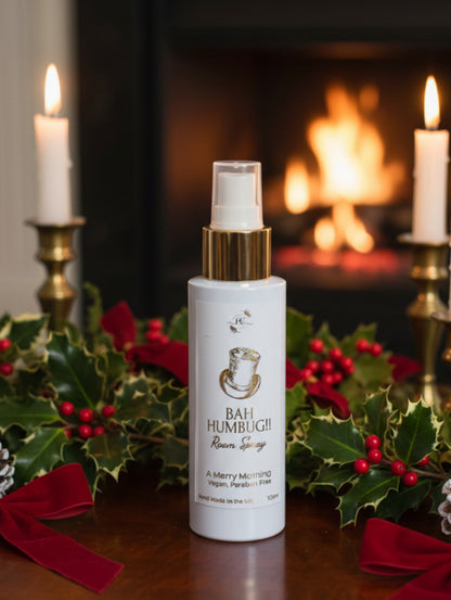 Festive Room Spray Bah Humbug by Hazel Glow, against background of a fireplace, holly and candles