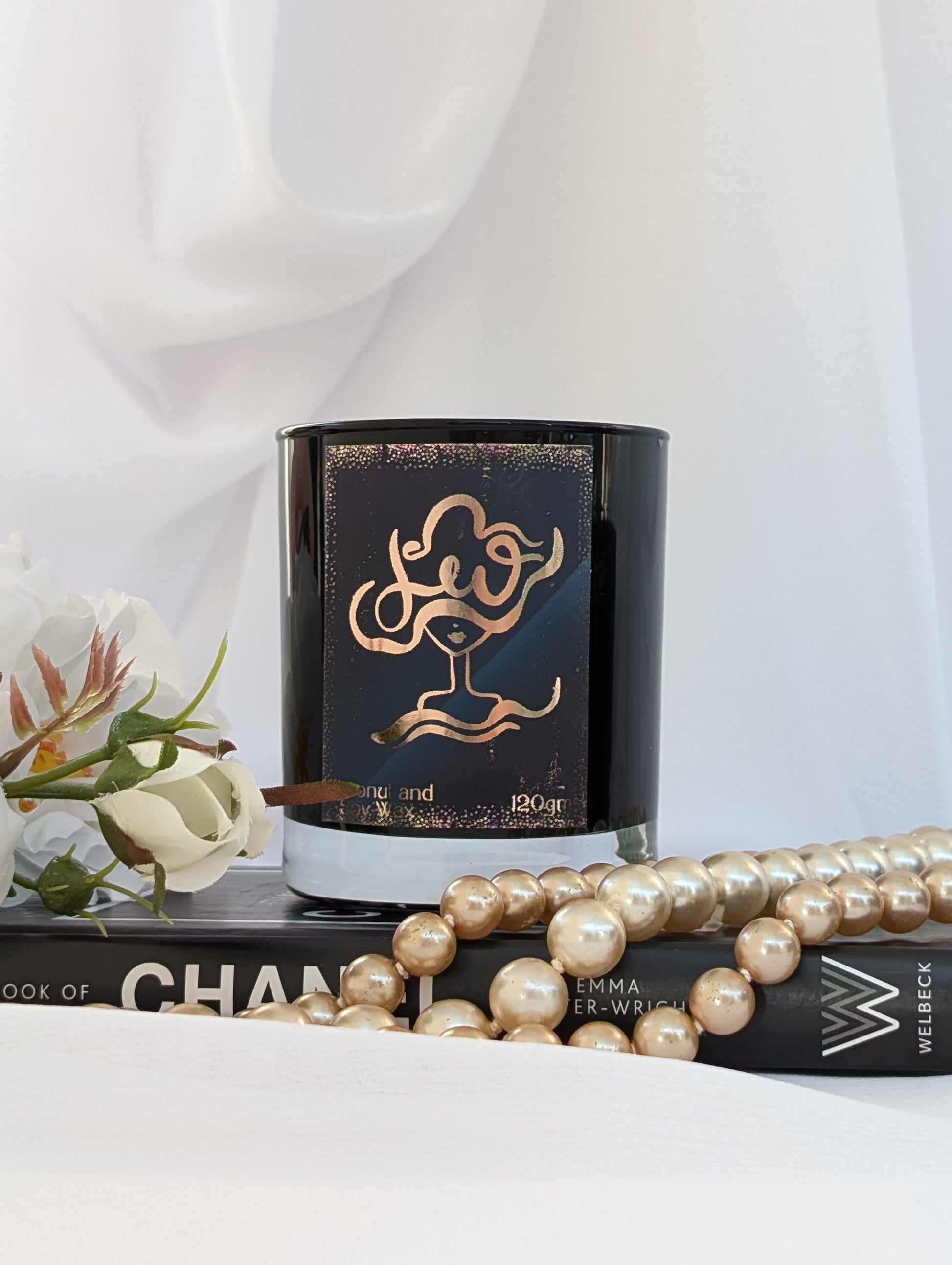 Black and Gold Leo Zodiac Candle on black book with pearls and flowers
