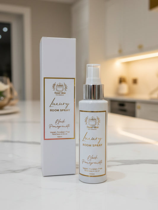 Room Spray by Hazel Glow in Black Pomegranate fragrance.  White bottle and packaging with white and gold foil label on white marble surface in luxury kitchen
