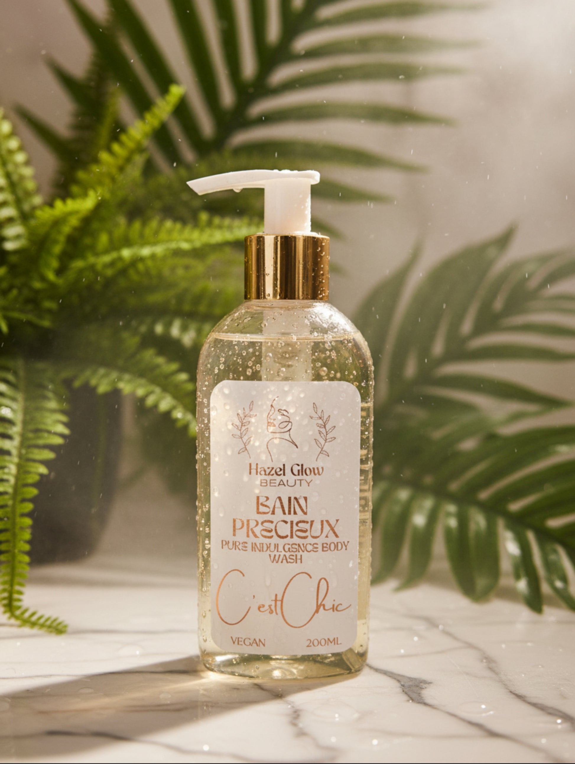 Hazel Glow Luxury Body Wash in C'est Chic fragrance.  200ml pump bottle on a marble surface with ferns in the background