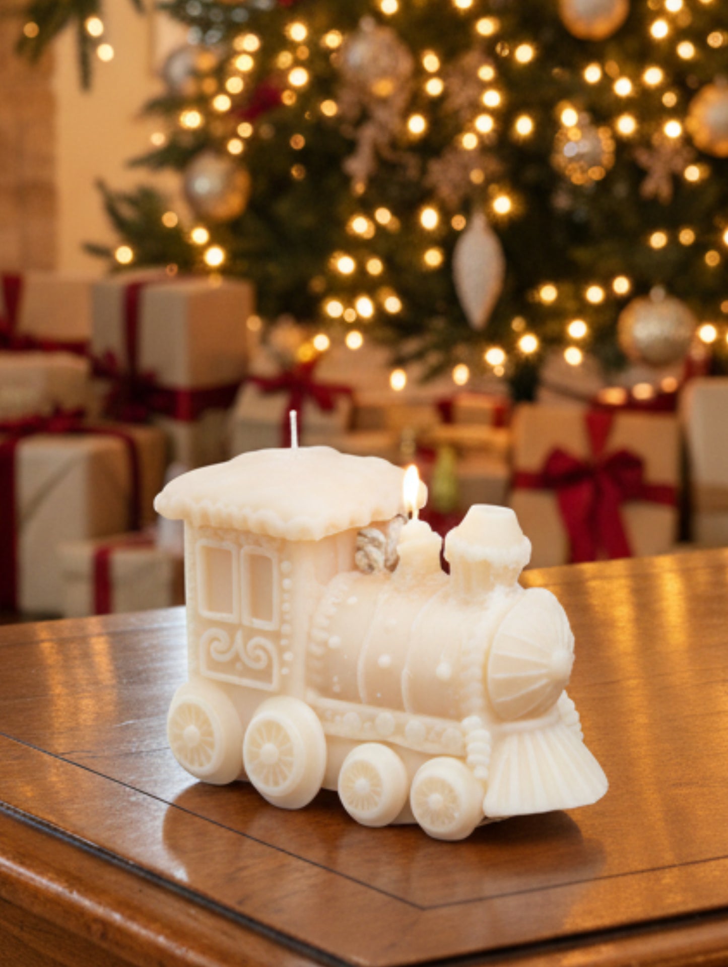 A cream-colored decorative train-shaped candle  on a wooden table with Christmas tree and presents in the background