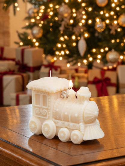 A cream-colored decorative train-shaped candle  on a wooden table with Christmas tree and presents in the background