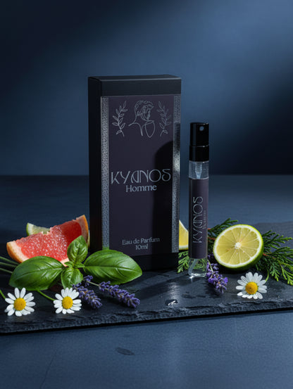 A 10ml perfume sample vial and its matching black packaging box for 'Kyanos Homme' Eau de Parfum, displayed with fragrance ingredients on a dark grey slate