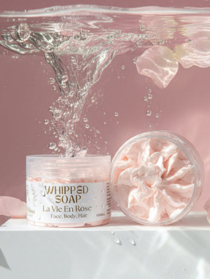Jar of La Vie en Rose Whipped Soap in water with rose petals