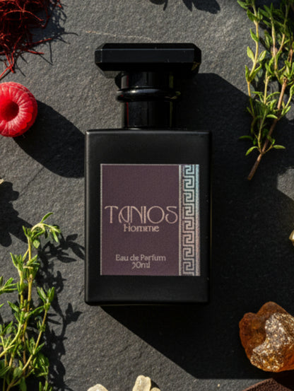 Tanios leather perfume for men by Hazel Glow.  Black bottle with black label and silver foil detail against a slate background with herbs and fruit