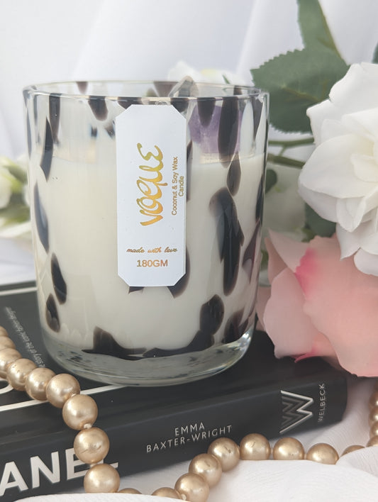 Luxury Candle in a glass jar with a leopard print pattern, placed on books with flowers and pearls around.