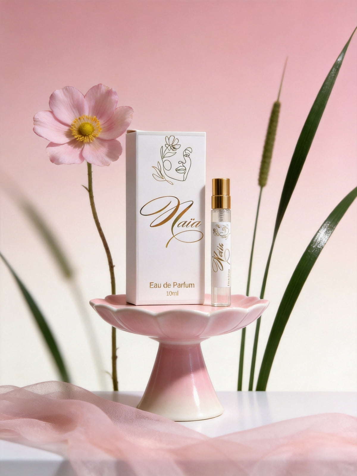 Naïa Eau De Parfum Discovery size by Hazel Glow against a pink background with pink gauze and flowers in the background