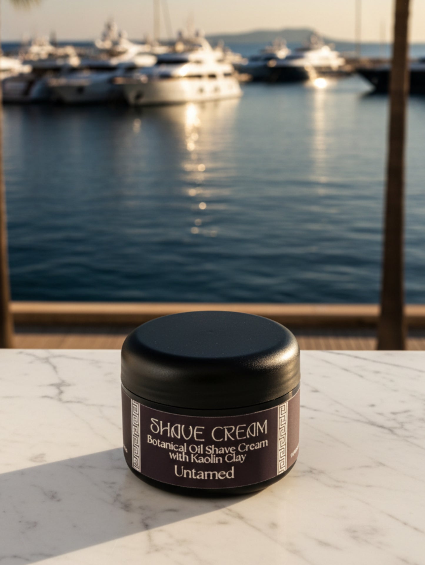 Jar of men's botanical oil shave cream, Untamed, fougere type fragrance by Hazel Glow.  On a marble surface with the sea and yachts in the background
