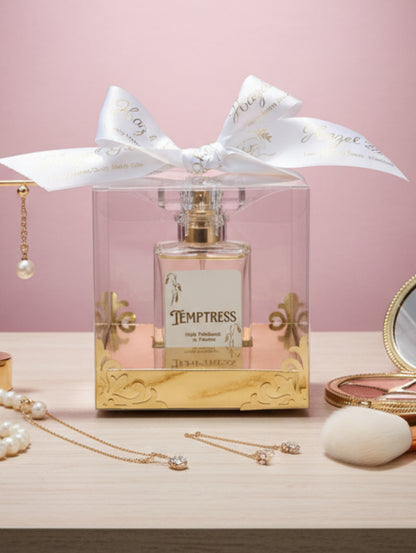 Perfume oil Temptress in a decorative box with a white ribbon on a dressing table with jewellery and make up