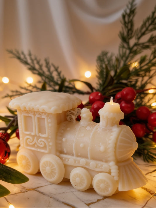 Christmas candle by Hazel Glow in the shape of a toy train against holly berries and sparkling lights