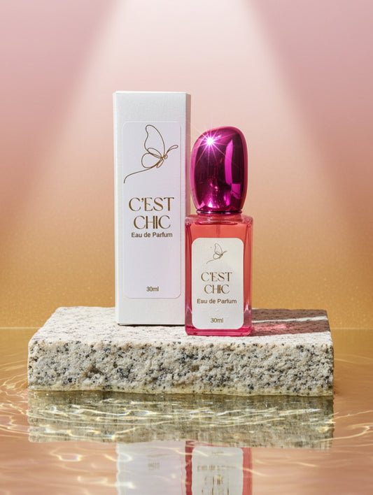Vegan refillable perfume C'est Chic in beautiful fuschia pink bottle with metallic fuschia pink lid, golden foil label.  On a stone plinth in water by Hazel Glow