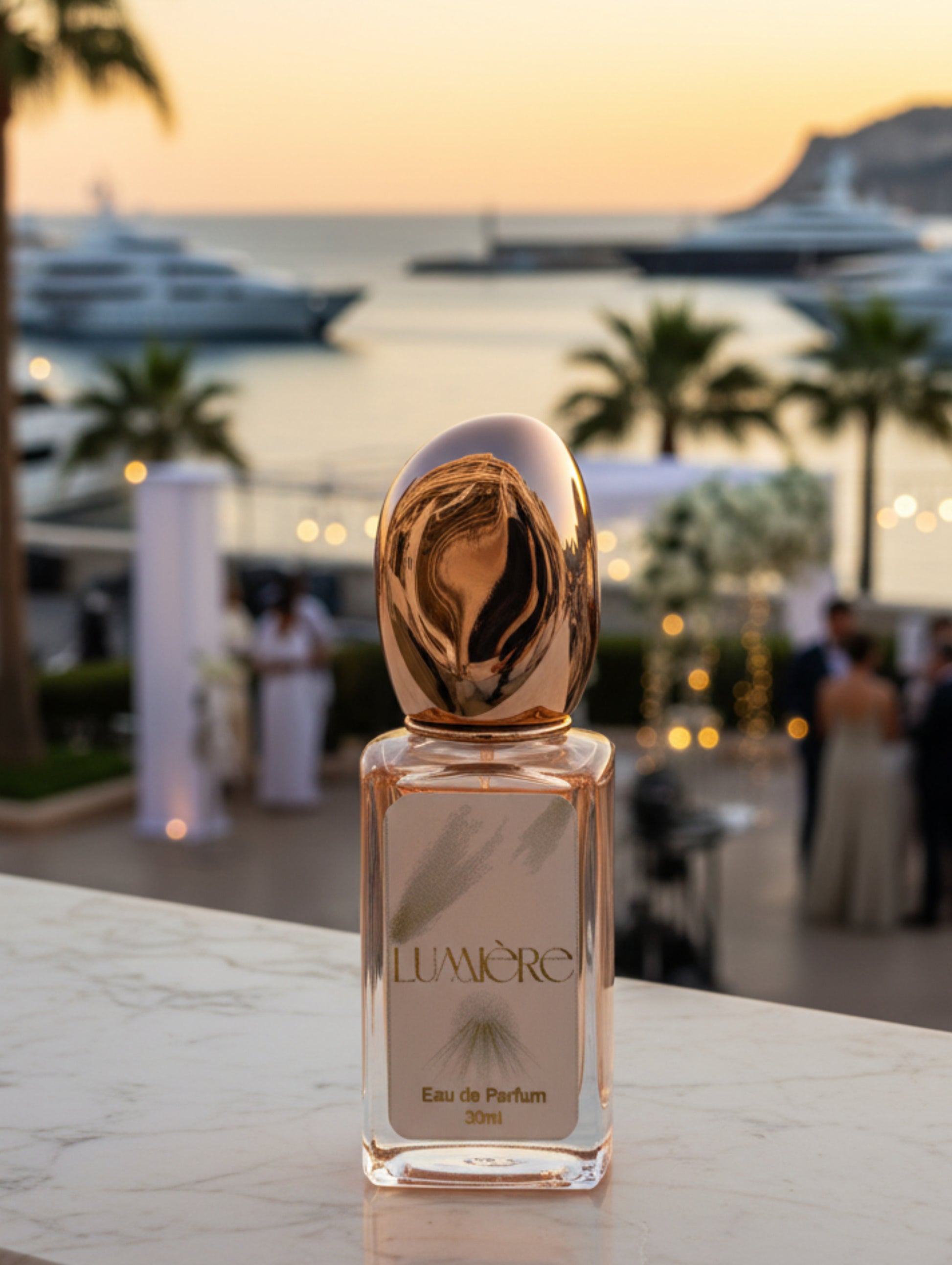 Lumiere vegan refillable bridal perfume in rose gold bottle with gold foiled label on a marble surface with Monaco in the background