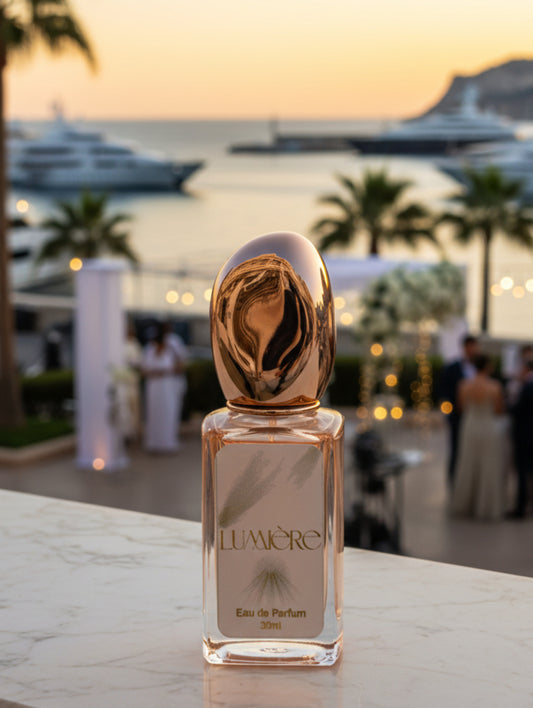 Lumiere vegan refillable bridal perfume in rose gold bottle with gold foiled label on a marble surface with Monaco in the background