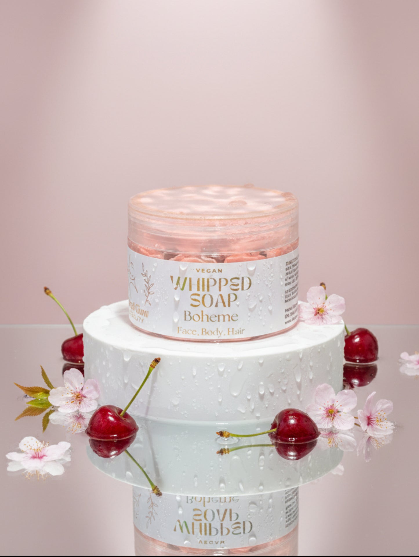 Vegan whipped soap Boheme by Hazel Glow.  jar on white plinth surrounded by cherries and cherry blossom
