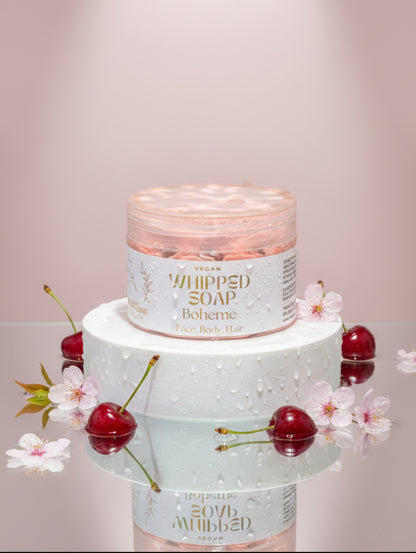 Vegan whipped soap Boheme by Hazel Glow.  jar on white plinth surrounded by cherries and cherry blossom