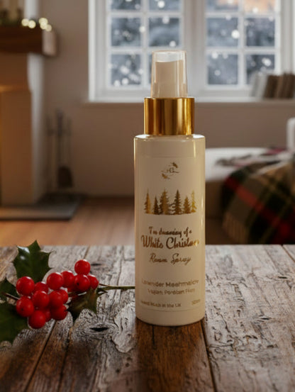 Festive fragrance room spray by Hazel Glow.  White Christmas in Lavender Marshmallow fragrance on a wooden table with holly in front of a window outside it is snowing