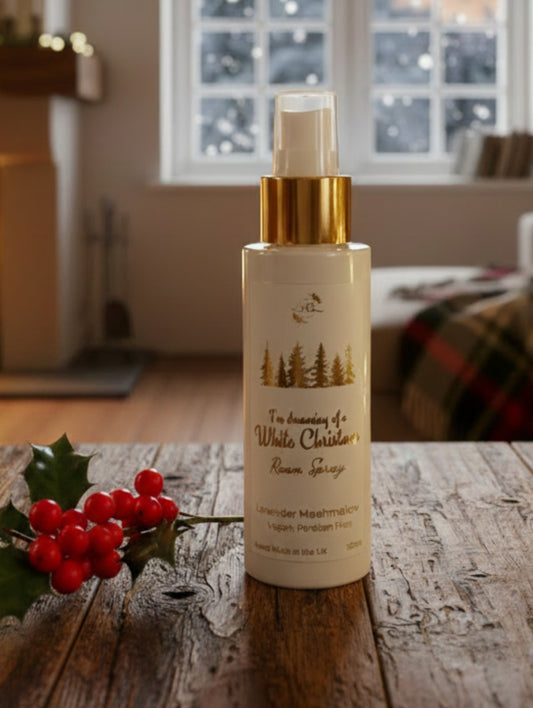 Festive fragrance room spray by Hazel Glow.  White Christmas in Lavender Marshmallow fragrance on a wooden table with holly in front of a window outside it is snowing